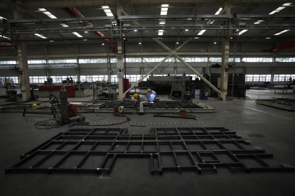 Workers wield a minibus chassis frames at a Tenglong Automobile Co. manufacturing factory during a media-organized tour in Xiangyang in central China's Hubei Province on May 10, 2023. China's manufacturing and consumer spending are weakening after a strong start to 2023 after anti-virus controls ended. (AP Photo/Andy Wong)