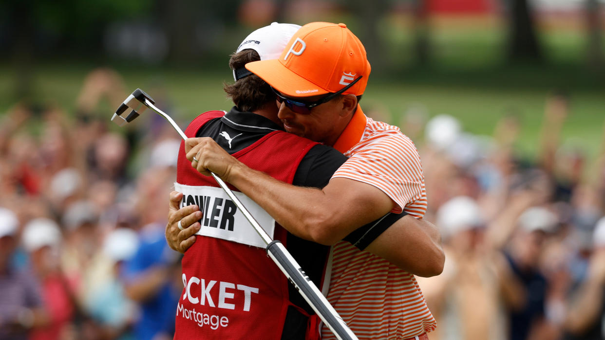  Rickie Fowler of the United States celebrates with his caddie, Ricky Romano, on the 18th green after winning on the first playoff hole during the final round of the Rocket Mortgage Classic 