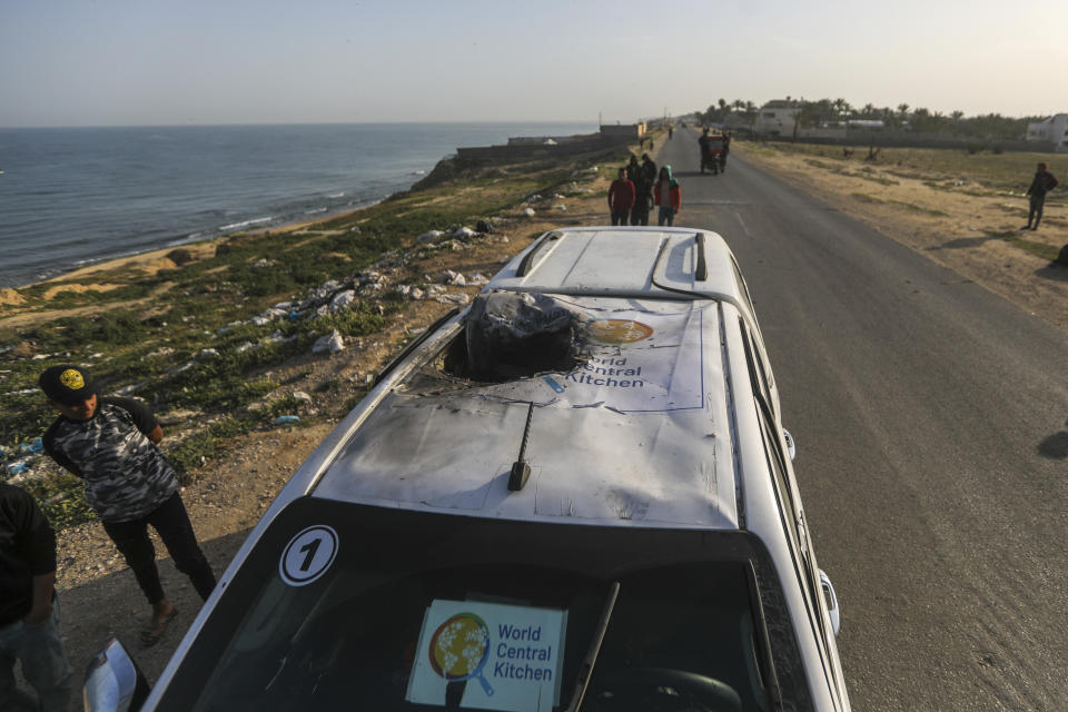 Palestinians inspect a vehicle with the logo of the World Central Kitchen wrecked by an Israeli airstrike in Deir al Balah, Gaza Strip, Tuesday, April 2, 2024. A series of airstrikes killed seven aid workers from the international charity, leading it to suspend delivery Tuesday of vital food aid to Gaza. (AP Photo/Ismael Abu Dayyah)