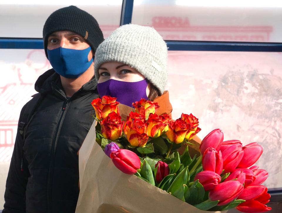 A couple with face masks walk with tulips on March 26, 2020 on a street of Warsaw, amid the novel coronavirus pandemic. - Polish government urged citizens to stay at home for a few weeks to limit the spread of the novel coronavirus. (Photo by JANEK SKARZYNSKI / AFP) (Photo by JANEK SKARZYNSKI/AFP via Getty Images)
