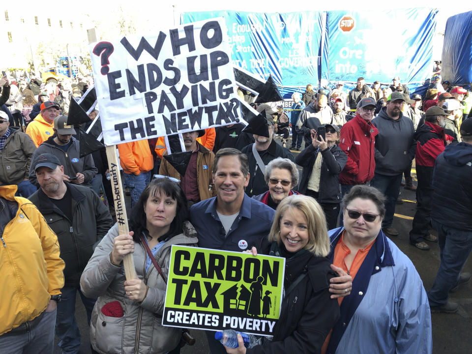 In this Thursday, Feb. 6, 2020, photo, Knute Buehler, a Republican candidate for U.S. Congress, poses with demonstrators who oppose a climate change bill written by majority Democrats in the statehouse at the Oregon State Capitol in Salem, Ore. Buehler, who distanced himself from President Donald Trump as he campaigned as the Republican nominee for governor of Oregon in 2018, now has fully embraced Trump as he seeks to fill a seat in Congress being vacated by Rep. Greg Walden, a Republican who is not seeking re-election. (AP Photo/Andrew Selsky)