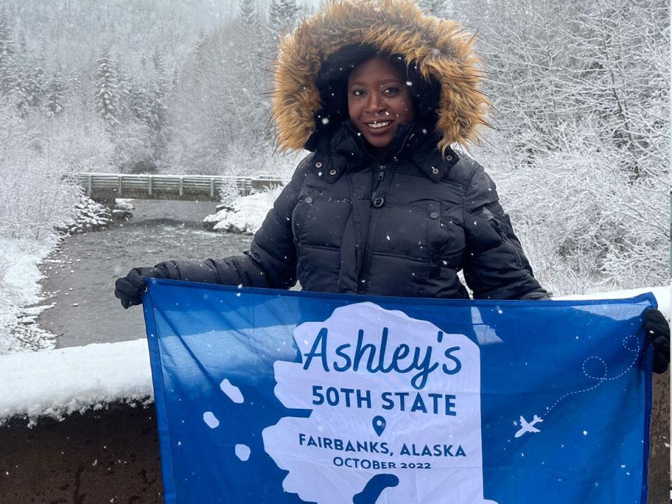 Ashley Nealy holding Alaska flag in front of winter weather