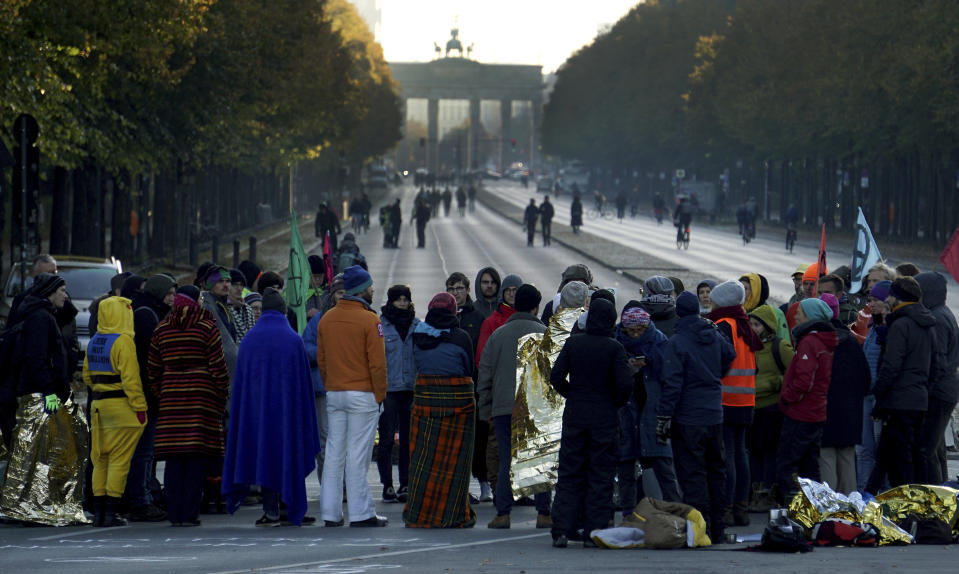 Supporters of the 'Extinction Rebellion' movement block a road between the Brandenburg Gate, background, and the Victory Column in Berlin, Germany, Monday, Oct. 7, 2019. The activists want to draw attention on the climate protest by blocking roads and with other acts of civil disobedience in Berlin and other cities around the world. (AP Photo/Michael Sohn)