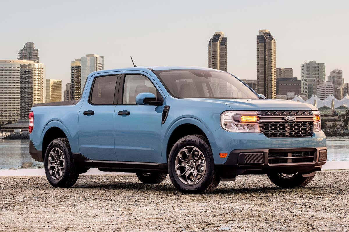 The 2022 Ford Maverick in blue sitting in front of a city skyline. We tested and reviewed the pickup and found a lot to love.