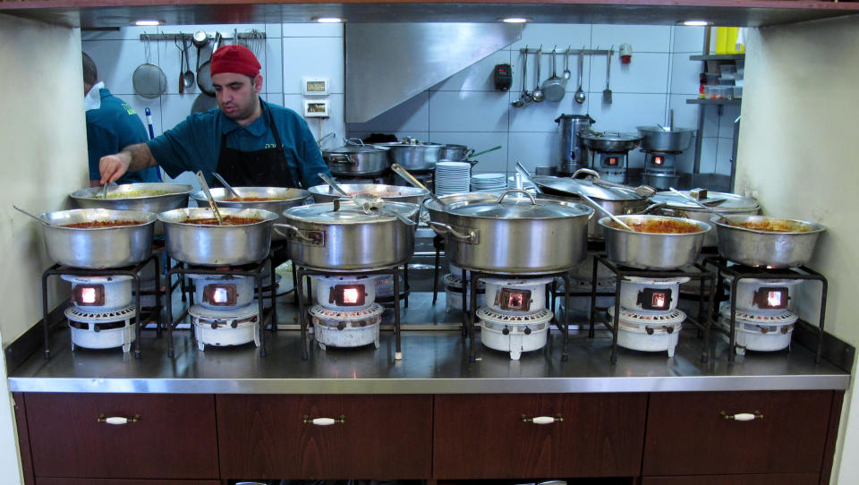 In this photo take Wednesday, March, 26, 2014, a cook tends to pots of food in the kitchen of at the Azura restaurant in Jerusalem's Mahane Yehuda market. The family-run institution is famous for its Turkish-inspired delicacies that are slow-cooked to perfection atop kerosene burners. (AP Photo/Aron Heller)