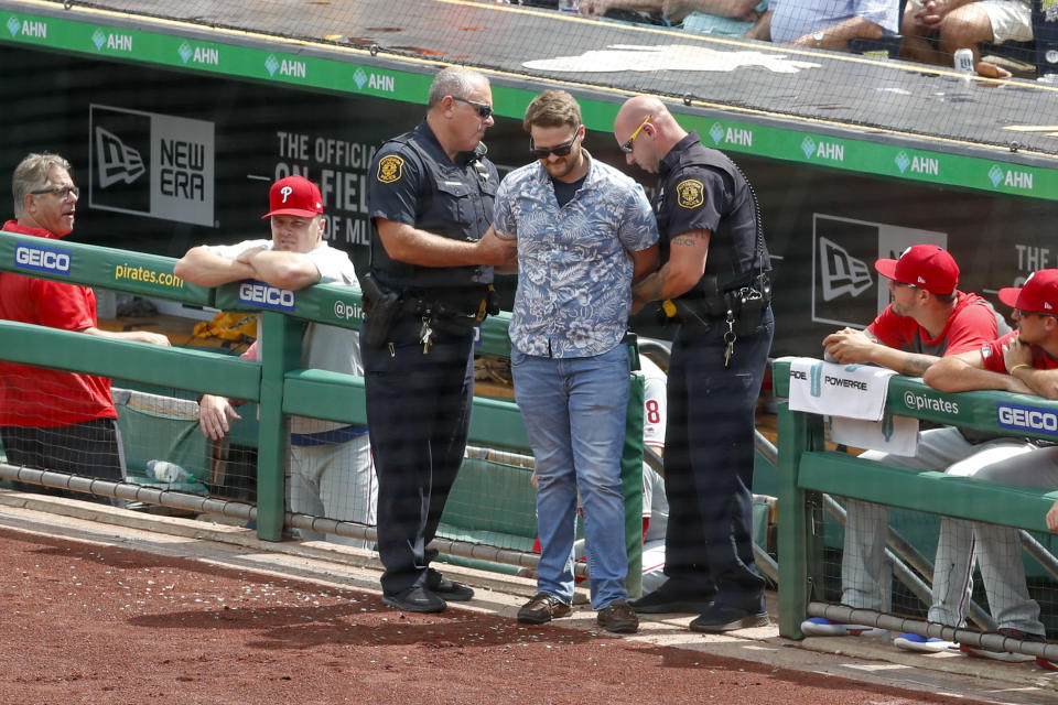 Police detain a man who walked across the field and approached Philadelphia Phillies' Brad Miller as he came to bat in the sixth inning of a baseball game against the Pittsburgh Pirates, Sunday, July 21, 2019, in Pittsburgh. The police took the man from the field and play continued. (AP Photo/Keith Srakocic)