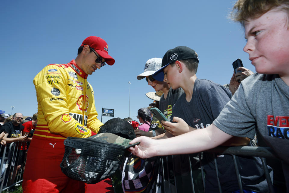 Joey Logano, left, gives autographs to fans before a NASCAR Cup Series auto race at Kansas Speedway in Kansas City, Kan., Sunday, May 7, 2023. (AP Photo/Colin E. Braley)