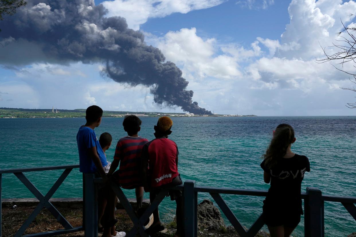 People watch a huge rising plume of smoke caused by a blaze at the Matanzas Supertanker Base, in Matazanas, Cuba, on Saturday.