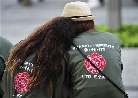 Two people with shirts commemorating New York City Fire Department firefighter Frankie Esposito sit at the South reflecting pool at the 9/11 Memorial during ceremonies marking the 12th anniversary of the 9/11 attacks on the World Trade Center in New York, September 11, 2013. REUTERS/Stan Honda/Pool