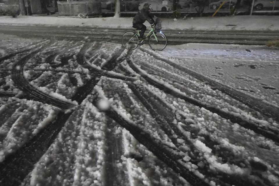 A person rides a bicycle under a snowfall, in Yokohama near Tokyo, Monday, Feb. 5, 2024. Japan Meteorological Agency warns more Metropolitan areas braced for snowfall Monday. (AP Photo/Eugene Hoshiko)