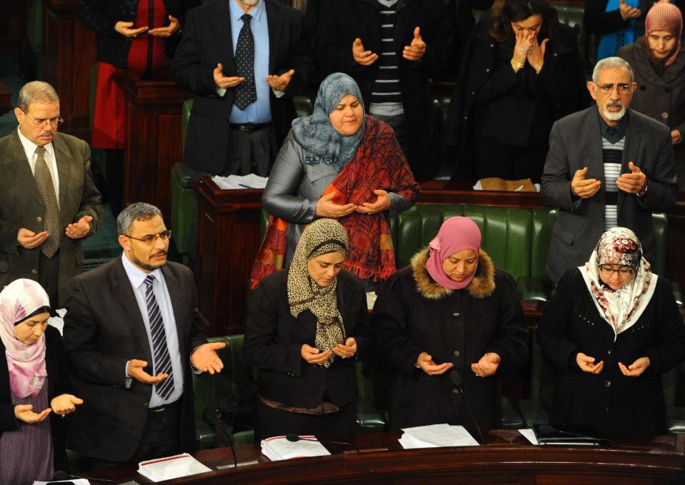 In this photo dated Thursday, Jan. 23, 2014, members of the Constitutional Assembly pray during a minute of silence for the passing of a late deputy, Mohamed Allouche, before a session as part of the debates on the new constitution in Tunis, Tunisia. The spokesman for Tunisia's Constitutional Assembly says a final vote on a new constitution will take place Saturday, now that members have approved each of the new articles in the historic document. (AP Photo/Hassene Dridi)