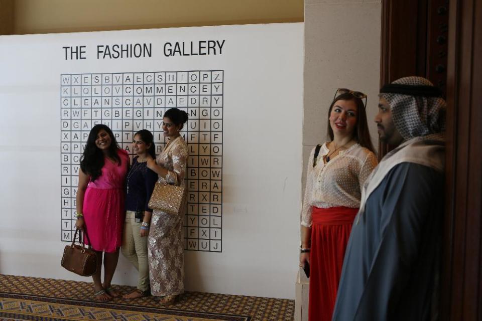 In this Thursday, Oct. 17, 2013 photo, an Arab man looks at the women posing for a photo during the Fashion Forward show in Dubai, United Arab Emirates. Dubai and luxury are nearly synonymous. The city is home to the world’s tallest tower, massive manmade islands in the shape of palm trees and a fleet of police cars that include a Ferrari, Lamborghini and a $2.5 million Bugatti Veyron. To boost its glamour factor and economy, the city has its eyes set on the multi-billion dollar a year global fashion industry, which is currently dominated by the U.S., Europe and Japan. (AP Photo/Kamran Jebreili)