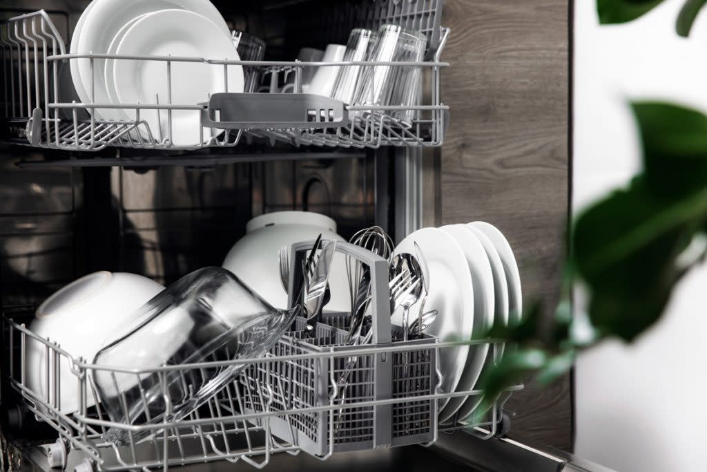 A dishwasher is open with clean dishes sitting in it. 