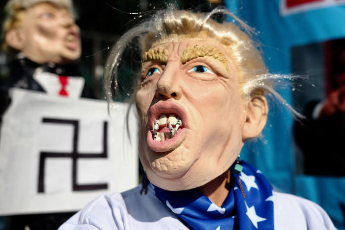 <p>An activist representing U.S President Donald Trump put fangs into a mask representing KKK members during a protest as part of the International Workers Day at the U.S embassy on May 01, 2017 in Mexico City. (Photo: Emilio Espejel/LatinContent/Getty Images) </p>