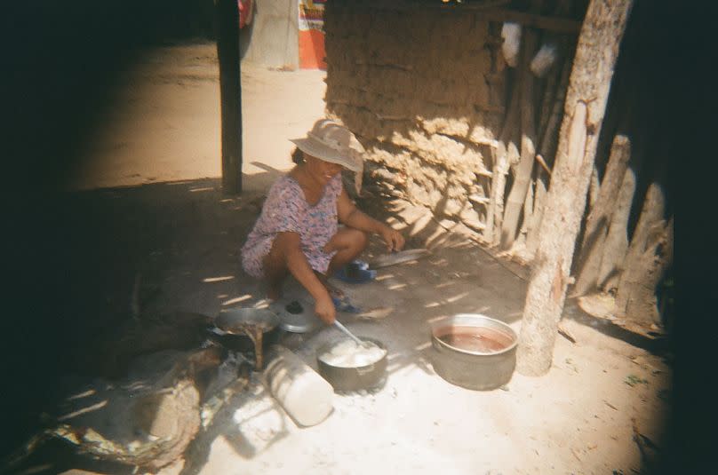 Ismael, de 14 años, toma una foto de su madre cocinando en la comunidad.