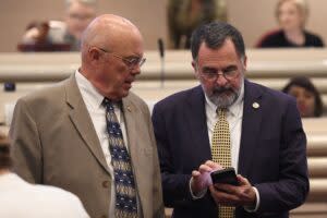 Two men in suits looking at a phone