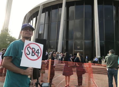 A protester against the Texas state law to punish "sanctuary cities" stands outside the U.S. Federal court in San Antonio, Texas, U.S., June 26, 2017. REUTERS/Jon Herskovitz