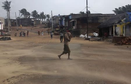 A man covers his face as wind blows dust near a beach in Gopalpur in Ganjam district in Odisha October 13, 2014. REUTERS/Stringer