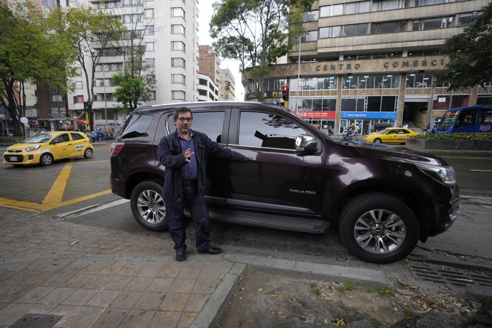 Alberto Yepes a leading human rights activist talks next to his government assigned SUV, during an interview in Bogota, Colombia, Friday, July 22, 2022. Yepes is concerned that cellular circuitry he discovered in the vehicle in September could be used to illegally eavesdrop on conversations. (AP Photo/Fernando Vergara)