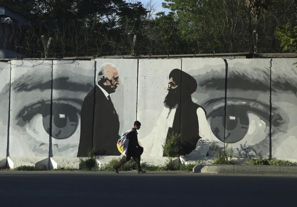 FILE - In this May 5, 2020 file photo, graffiti depicts Washington's peace envoy Zalmay Khalilzad, left, and Mullah Abdul Ghani Baradar, the leader of the Taliban delegation, in Kabul, Afghanistan. After 20 years America is ending its “forever” war in Afghanistan. The U.S. and NATO leave behind an Afghanistan that is at least half run directly or indirectly by the Taliban. (AP Photo/Rahmat Gul, File)