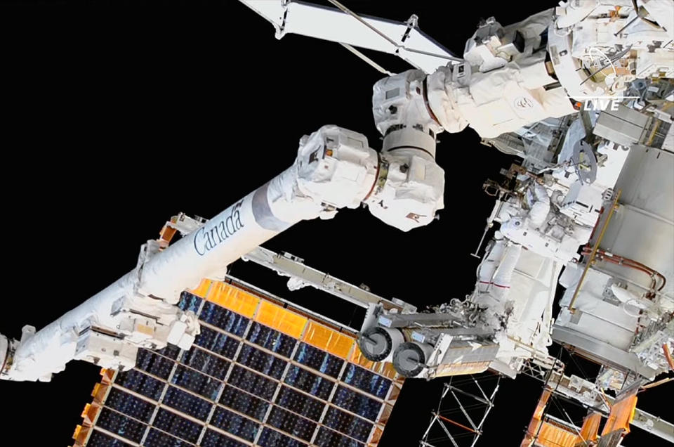 two nasa astronauts spacewalk near the international space station's solar arrays