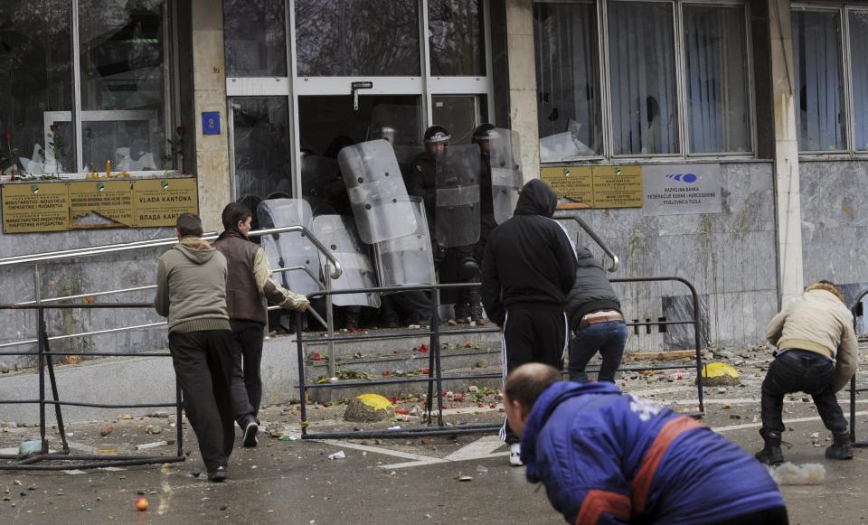 Bosnian police forces secure the entrance as protesters stoned a local government building in the Bosnian town of Tuzla, 140 kms north of Sarajevo, Thursday, Feb. 6, 2014. Several hundred protesters clashed with police as they tried to storm into the building of the local government and confront the officials there whom they blame for allowing the city's major state-owned companies to go bankrupt after dubious privatizations. The four former state-owned companies that employed most of Tuzla's population were sold but the contracts obliged the new owners to invest in them and make them profitable. But those just sold the assets, stopped paying workers, and filed for bankruptcy. The authorities did nothing about such violation of sales contracts.(AP Photo/Darko Zabus)