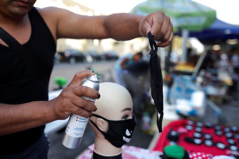 A street vendor uses a spray to check the effectiveness of a mask, during a preventive quarantine after the outbreak of the coronavirus disease (COVID-19), in Santiago