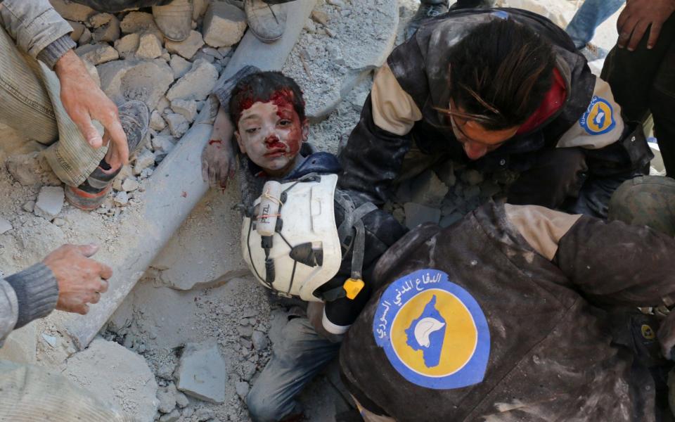 Syrian civil defence volunteers, known as the White Helmets, rescue a boy from the rubble following a reported barrel bomb attack on the Bab al-Nairab neighbourhood of Aleppo  - AFP