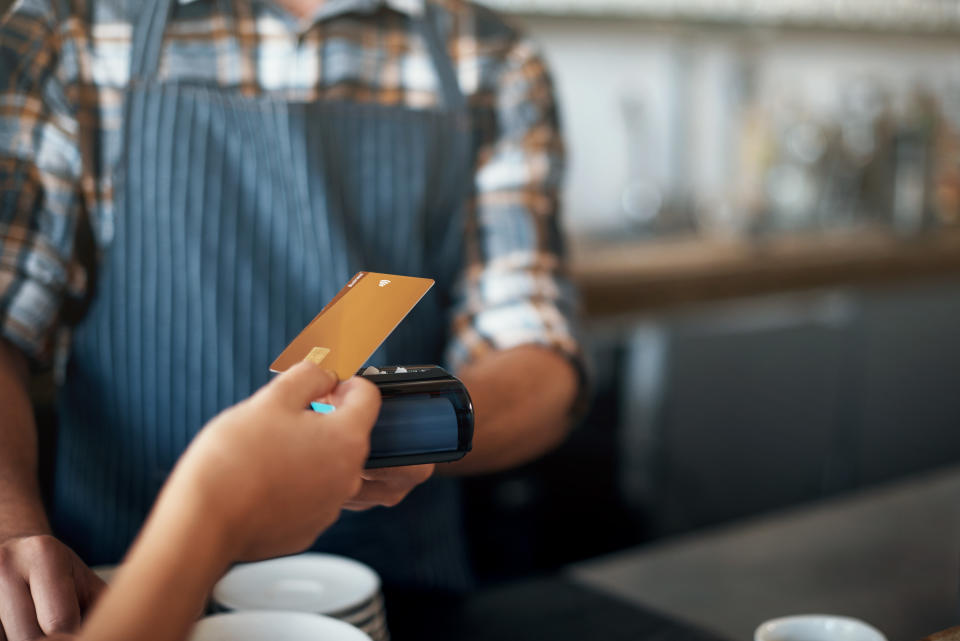 Closeup shot of a unrecognizable person giving a barman a credit card as payment inside of a restaurant