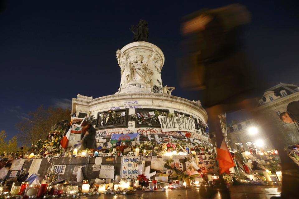 A woman walks past the statue at the Place de la Republique which is covered with flowers, messages and flags,on the eve of a ceremony to pay tribute for the victims of shooting attacks in Paris, France, November 26, 2015. The French President called on all French citizens to hang the tricolour national flag from their windows on Friday to pay tribute to the victims of the Paris attacks. (REUTERS/Jacky Naegelen)