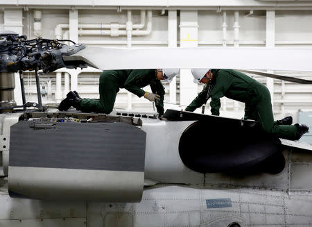 Flight crews work on a SH-60K Sea Hawk helicopter in the hangar deck of Japanese helicopter carrier Kaga in the Indian Ocean, Indonesia September 23, 2018. Picture taken September 23, 2018. REUTERS/Kim Kyung-Hoon