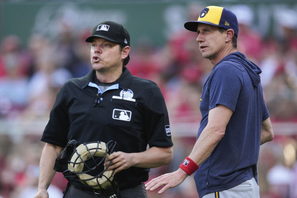 Milwaukee Brewers manager Craig Counsell, right, speaks with umpire DJ Reyburn during a stoppage in play in the seventh inning of the team's baseball game against the Cincinnati Reds in Cincinnati, Friday, June 2, 2023. (AP Photo/Jeff Dean)