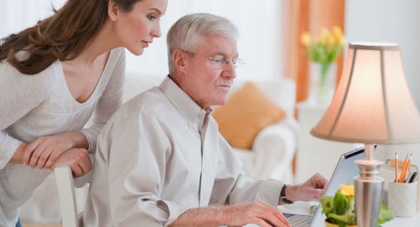 Daughter helping senior father with computer