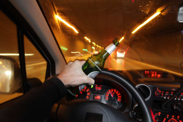 A car driver is drinking beer while he is driving through a tunnel