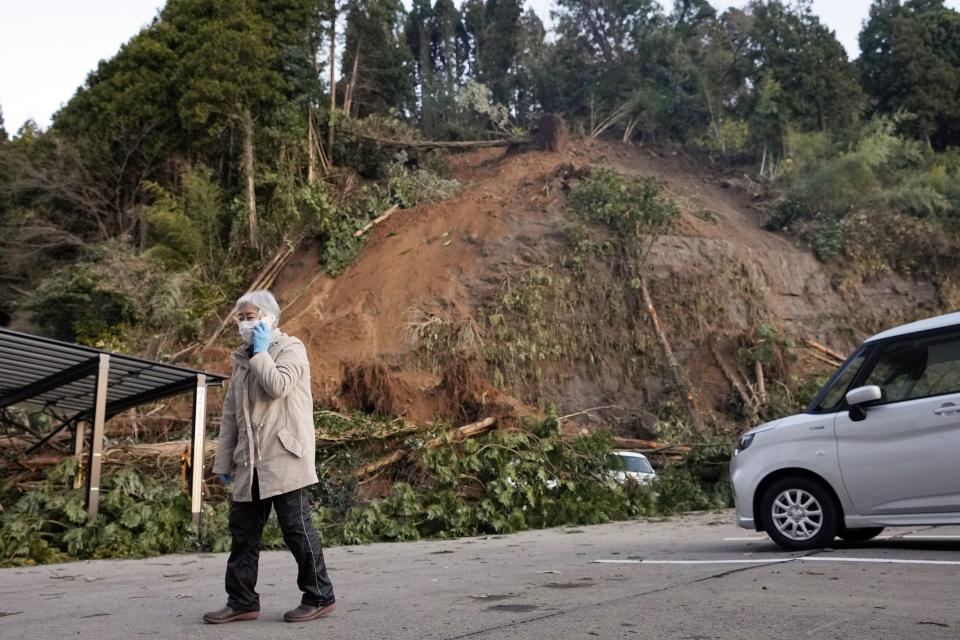 A person calls on a mobile phone near a landslide triggered by powerful earthquake in Anamizu in the Noto peninsula facing the Sea of Japan, northwest of Tokyo, Thursday, Jan. 4, 2024. More soldiers have been ordered to bolster the rescue operations Thursday, providing those in need with drinking water, hot meals and setting up bathing facilities after a magnitude 7.6 quake hit Ishikawa Prefecture and nearby regions Monday. (AP Photo/Hiro Komae)