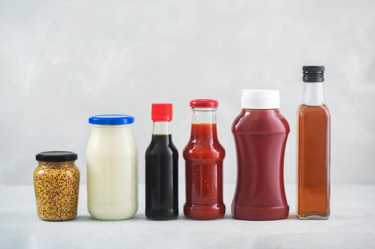 A set of different sauces in a bottles on the table, gray background. Ketchup, mayonnaise, barbecue, soy, balsamic and etc