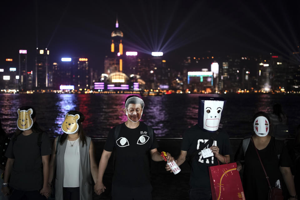 A protester wearing a mask depiting Chinese President Xi Jinping attends a protest with others in Hong Kong, Friday, Oct. 18, 2019. Hong Kong pro-democracy protesters are donning cartoon/superhero masks as they formed a human chain across the semiautonomous Chinese city, in defiance of a government ban on face coverings. (AP Photo/Felipe Dana)