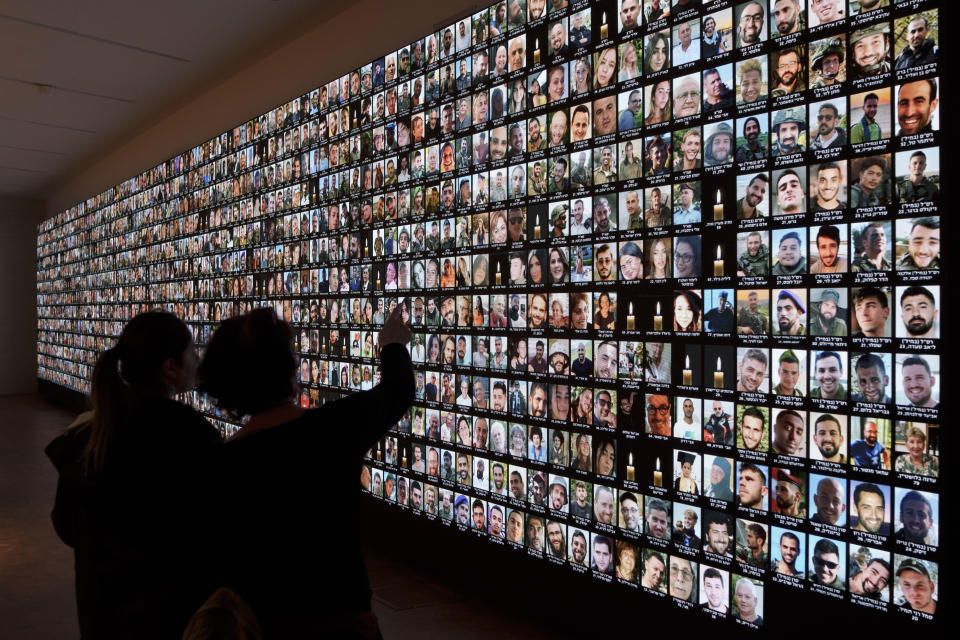 FILE - Visitors look at photos of Israeli people who were killed during Hamas militants attack on Oct. 7 and those who died during the Israel-Hamas war in the Gaza Strip, displayed on a giant screen at the National Library in Jerusalem, Israel, Sunday, Jan. 28, 2024. Netanyahu is under mounting pressure from families of the hostages and the wider public to reach a deal with Hamas to bring the captives home. Many Israelis fear time is running out. (AP Photo/Leo Correa, File)