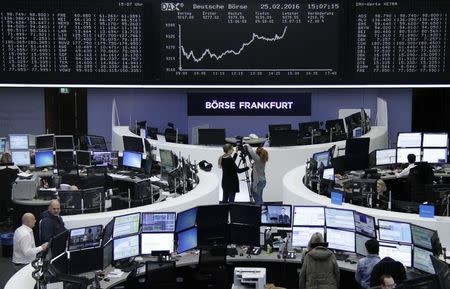 Traders work at their desks in front of the German share price index, DAX board, at the stock exchange in Frankfurt, Germany, February 25, 2016. REUTERS/Staff/Remote