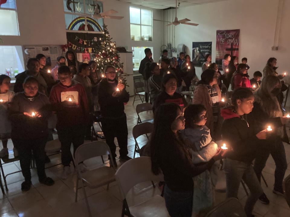 Guests at the Buen Samaritano shelter for migrants participate in a candle lighting ceremony at the shelter's small Methodist church in anticipation of Christmas in Ciudad Juárez, Mexico, across from El Paso, Texas, on Thursday, Dec. 22, 2022. Tens of thousands of migrants who fled violence and poverty will spend Christmas in crowded shelters or on the dangerous streets of Mexican border towns. The Biden administration asked the Supreme Court not to lift pandemic-era restrictions on asylum-seekers before the holiday weekend.(AP Photo/Morgan Lee)