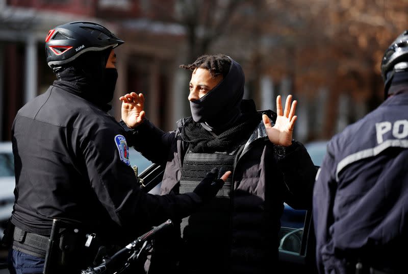 A man is searched by law enforcement personnel near the statue of Confederate general Robert E. Lee in Richmond, Virginia