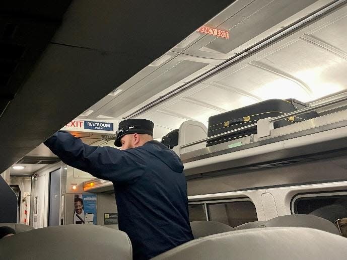 train conductor putting luggage on top level of amtrak train