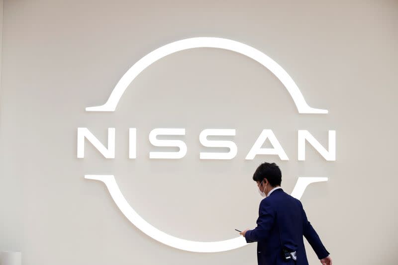FILE PHOTO: Man walks in front of the Nissan logo at Nissan Gallery in Yokohama