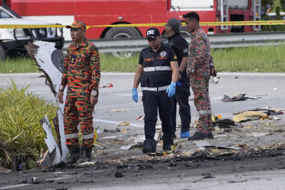 Members of the fire and rescue department inspect the crash site of a small plane in Shah Alam district, Malaysia, Thursday, Aug. 17, 2023. Police say a small aircraft has crashed in the suburb of Malaysia's central Selangor state, with multiple bodies recovered. (AP Photo/Vincent Thian)