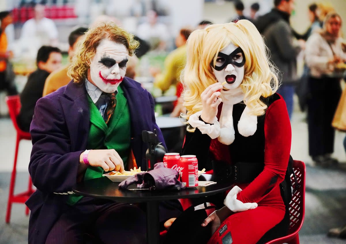 Cosplayers dressed as characters the Joker (left) and Harlequin (right) during MCM Comic Con in London in 2021. (PA)