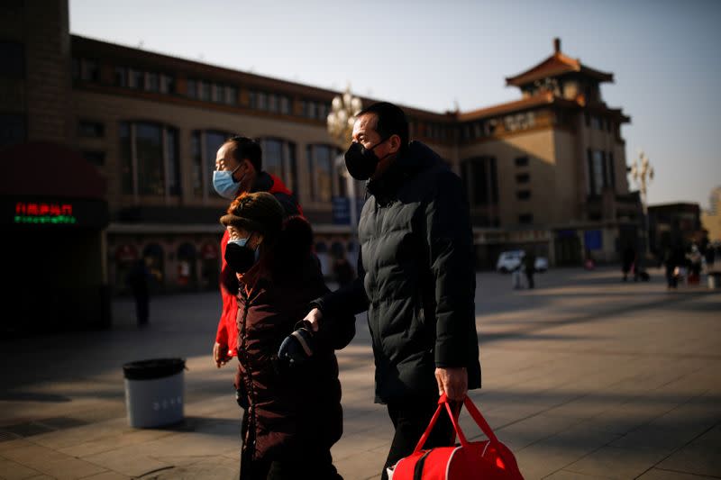 People wearing face masks walks outside Beijing Railway Station as the country is hit by an outbreak of the new coronavirus, in Beijing