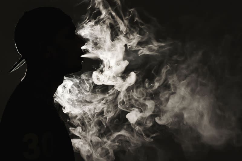 Portrait of a man vaping with his face partially covered by vapour. ― Picture by Yusof Mat Isa