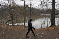 A woman walks the trail near Lower Shaker Lake, Tuesday, Dec. 7, 2021, in Cleveland Heights, Ohio. In 2021, the cities of Cleveland Heights and Shaker Heights approved a $28.3 million plan to remove Horseshoe Lake Dam, return the area to a free-flowing stream and rebuild Lower Shaker Lake Dam. (AP Photo/Tony Dejak)