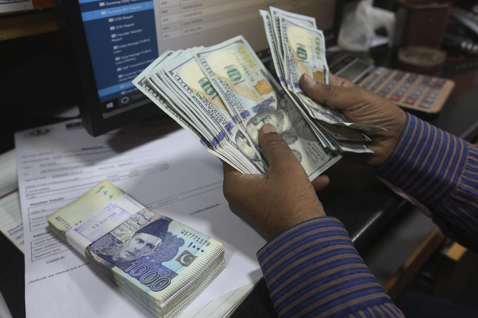 A Pakistani money trader counts U.S. dollars for a customer at a currency exchange office, in Karachi, Pakistan, Thursday, May 19, 2022. Pakistan’s currency has plummeted to an all-time record low in intraday trading against the U.S. dollar amid uncertainty about the success of crucial talks between the International Monetary Fund and the government of Prime Minister Shahbaz Sharif, which is considering massive new taxation to avoid a default. (AP Photo/Fareed Khan)