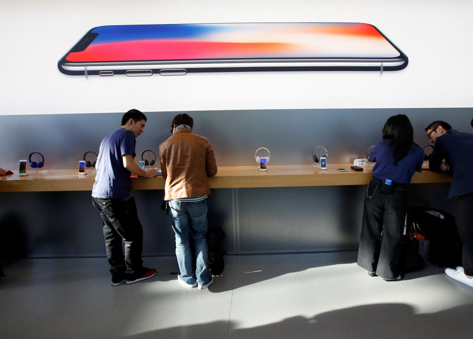 Customers are seen under a picture of Apple’s new iPhone X after it goes on sale at the Apple Store in Tokyo